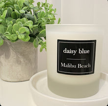 Daisy Blue Home Fragrance Mariette Candle Jar with a glass container and a lit candle inside, soft glow illuminating the jar.