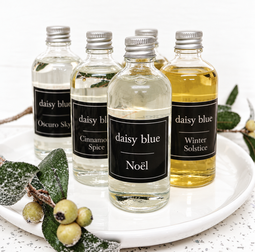 Winter reed diffuser refills by Daisy Blue Home Fragrance displayed on a white tray with fragrance oils and reed sticks.