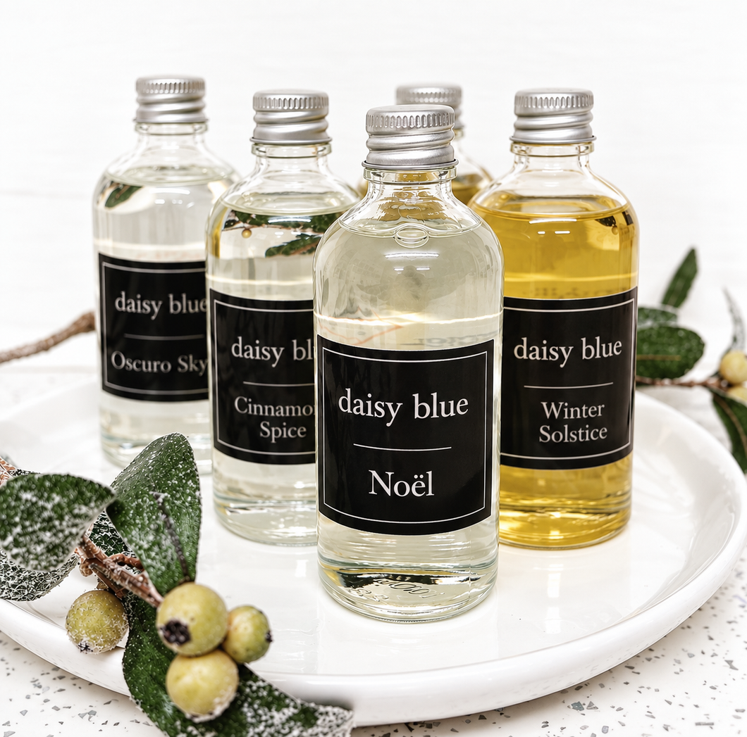Winter reed diffuser refills by Daisy Blue Home Fragrance displayed on a white tray with fragrance oils and reed sticks.